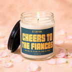 Lit candle with label reading "Attention: Cheers to the Fiances" surrounded by pink petals.