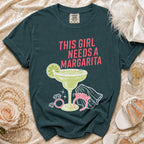 Dark teal t-shirt with "This Girl Needs A Margarita" text and margarita graphic.