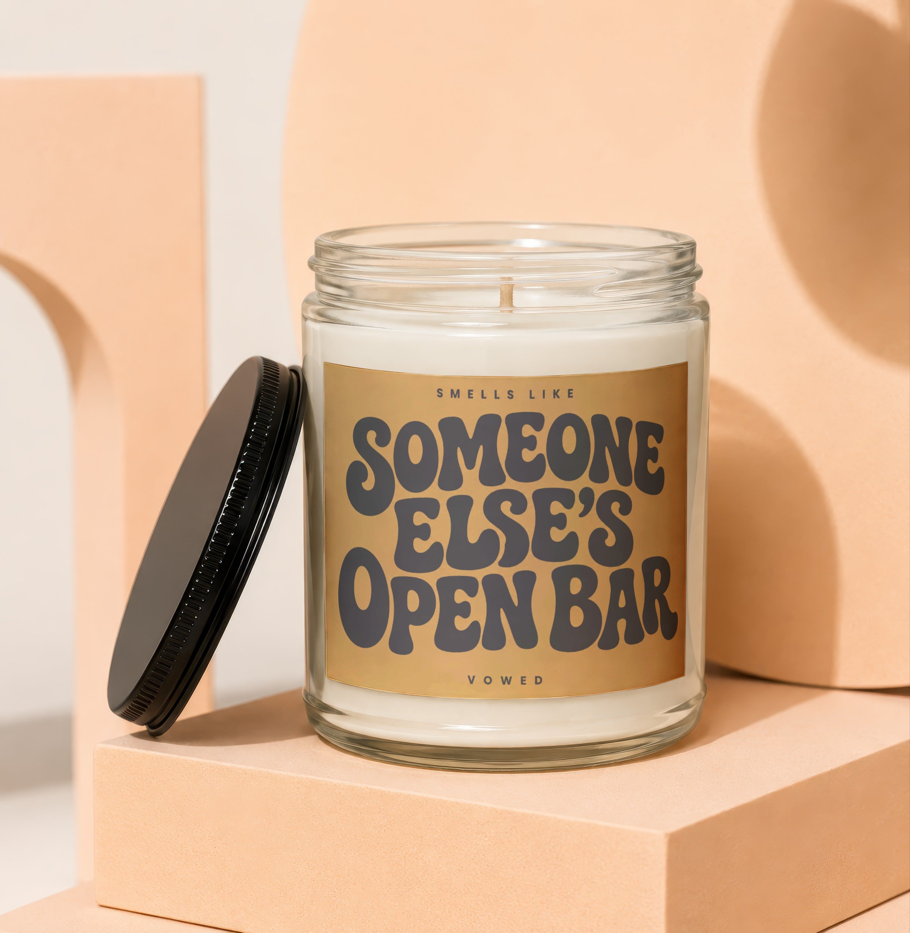 Candle with gold label reading "Smells like Someone Else's Open Bar"