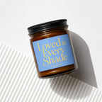Amber jar candle with blue label reading "Loved in Every Shade" and "vowed".