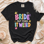 Black t-shirt with "BRIDE BUT MAKE IT WEIRD" text in colorful, patterned letters.