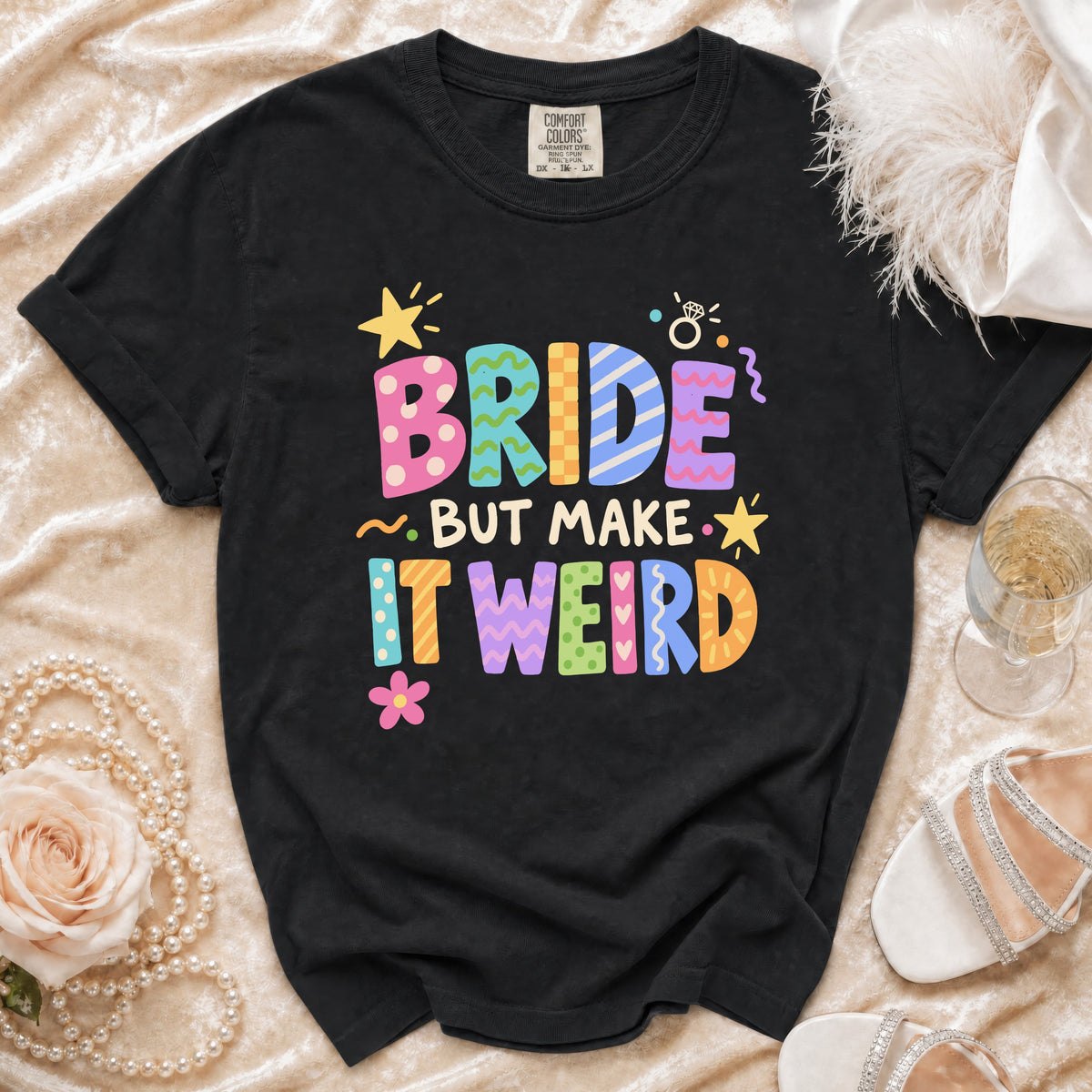 Black t-shirt with "BRIDE BUT MAKE IT WEIRD" text in colorful, patterned letters.