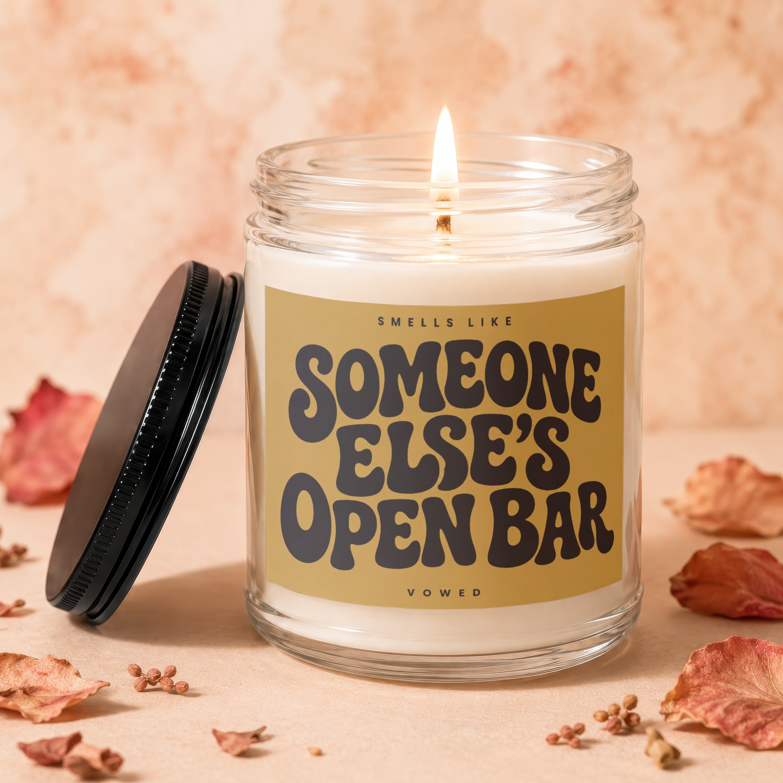 Glass jar candle with lit wick, reads "Smells Like Someone Else's Open Bar".