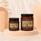 Two amber candles with purple labels reading "Survived the Family Drama."