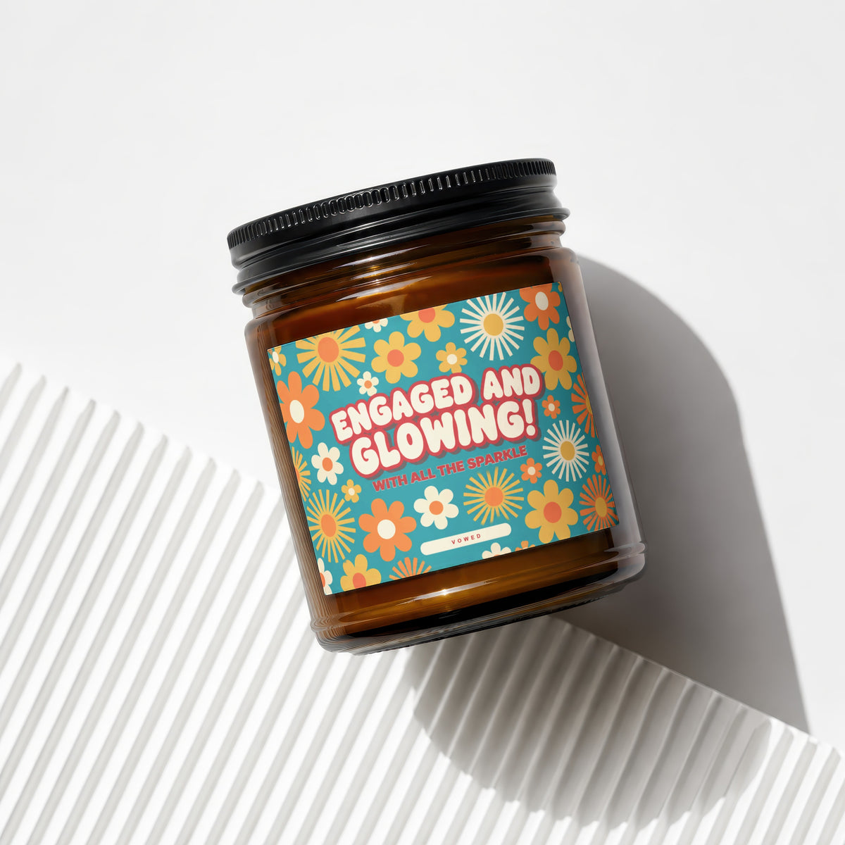 Amber jar candle with "ENGAGED AND GLOWING! WITH ALL THE SPARKLE" text and floral pattern.