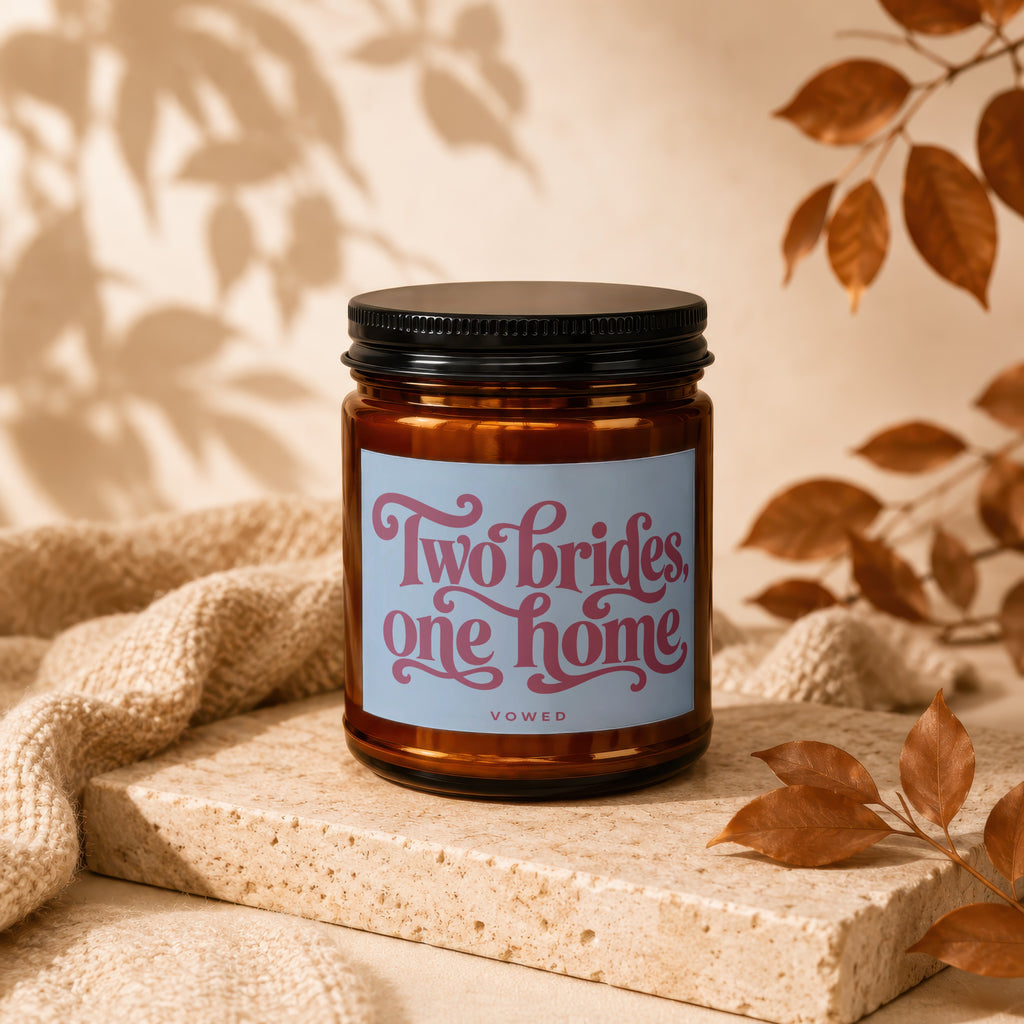 Glass candle with "Two brides, one home" text, "VOWED" brand.