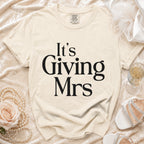 Cream t-shirt with black text "It's Giving Mrs" and Comfort Colors tag.