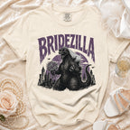 Cream t-shirt with "BRIDEZILLA" text featuring Godzilla in a wedding veil and heart sunglasses.