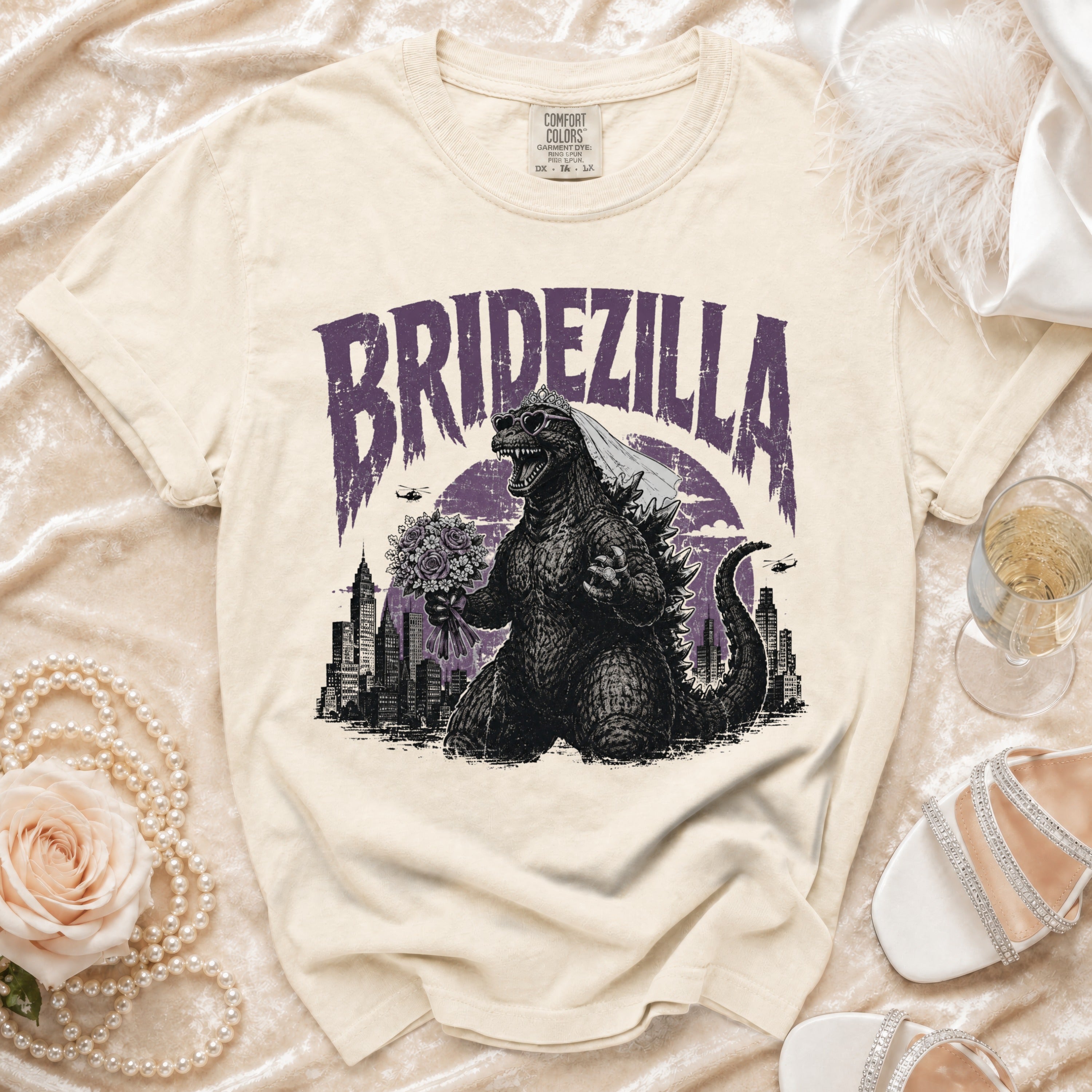 Cream t-shirt with "BRIDEZILLA" text featuring Godzilla in a wedding veil and heart sunglasses.