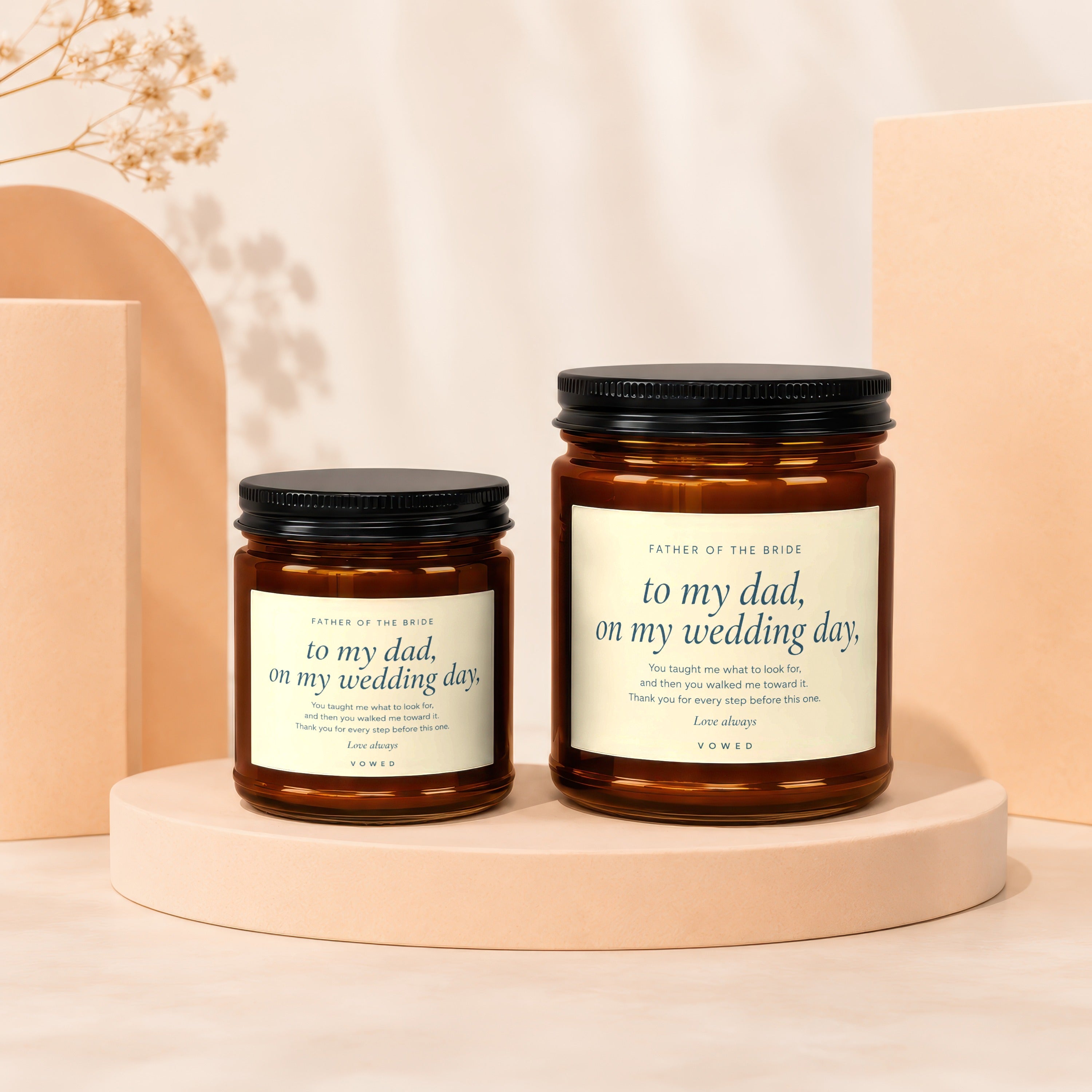 Two amber glass candles with black lids, featuring text for "Father of the Bride".