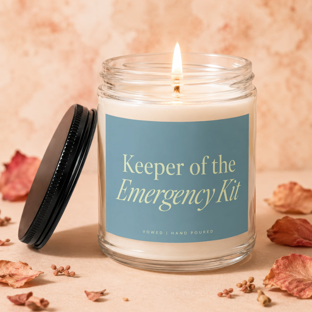 Lit glass jar candle with label "Keeper of the Emergency Kit".