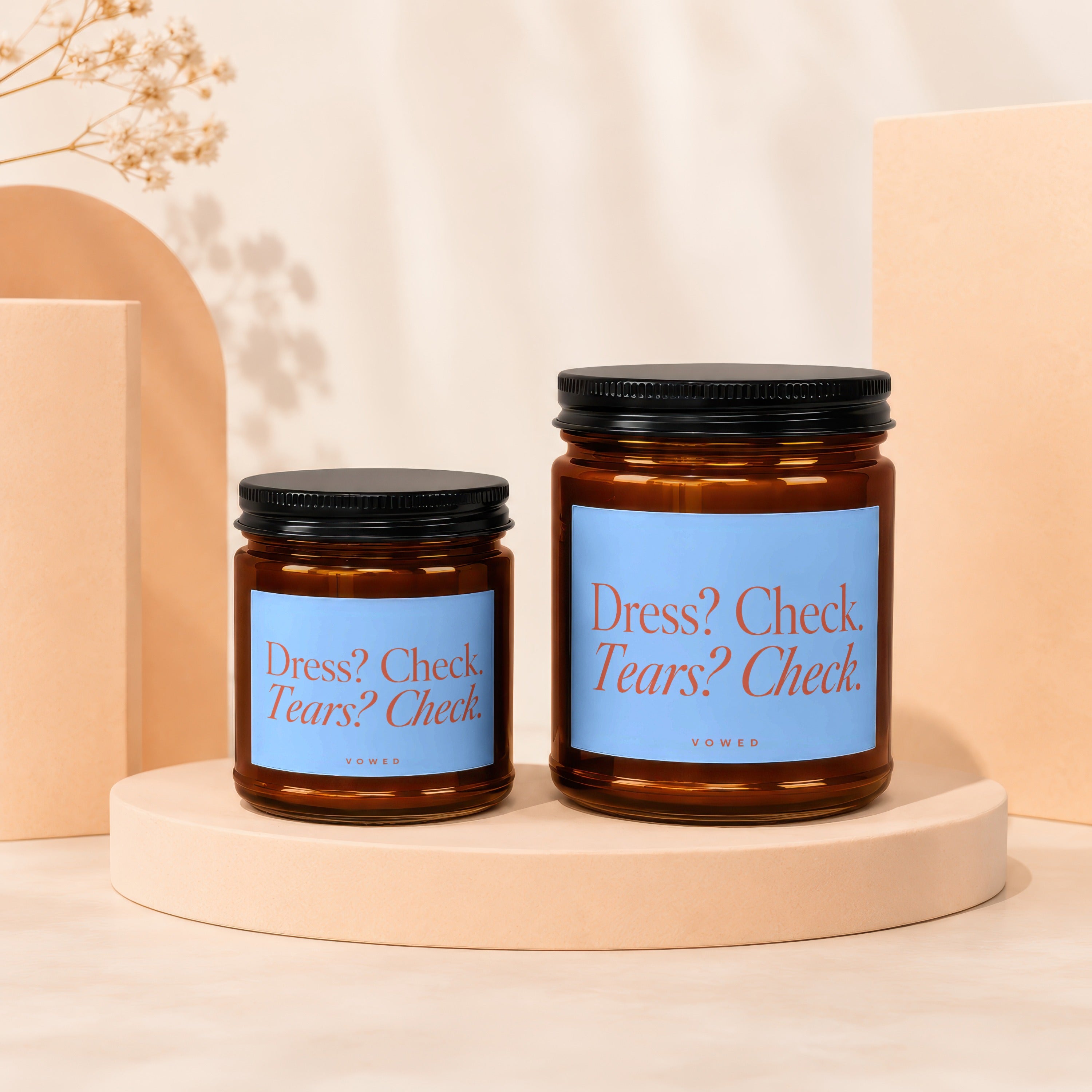 Two amber glass candles with blue labels reading "Dress? Check. Tears? Check."