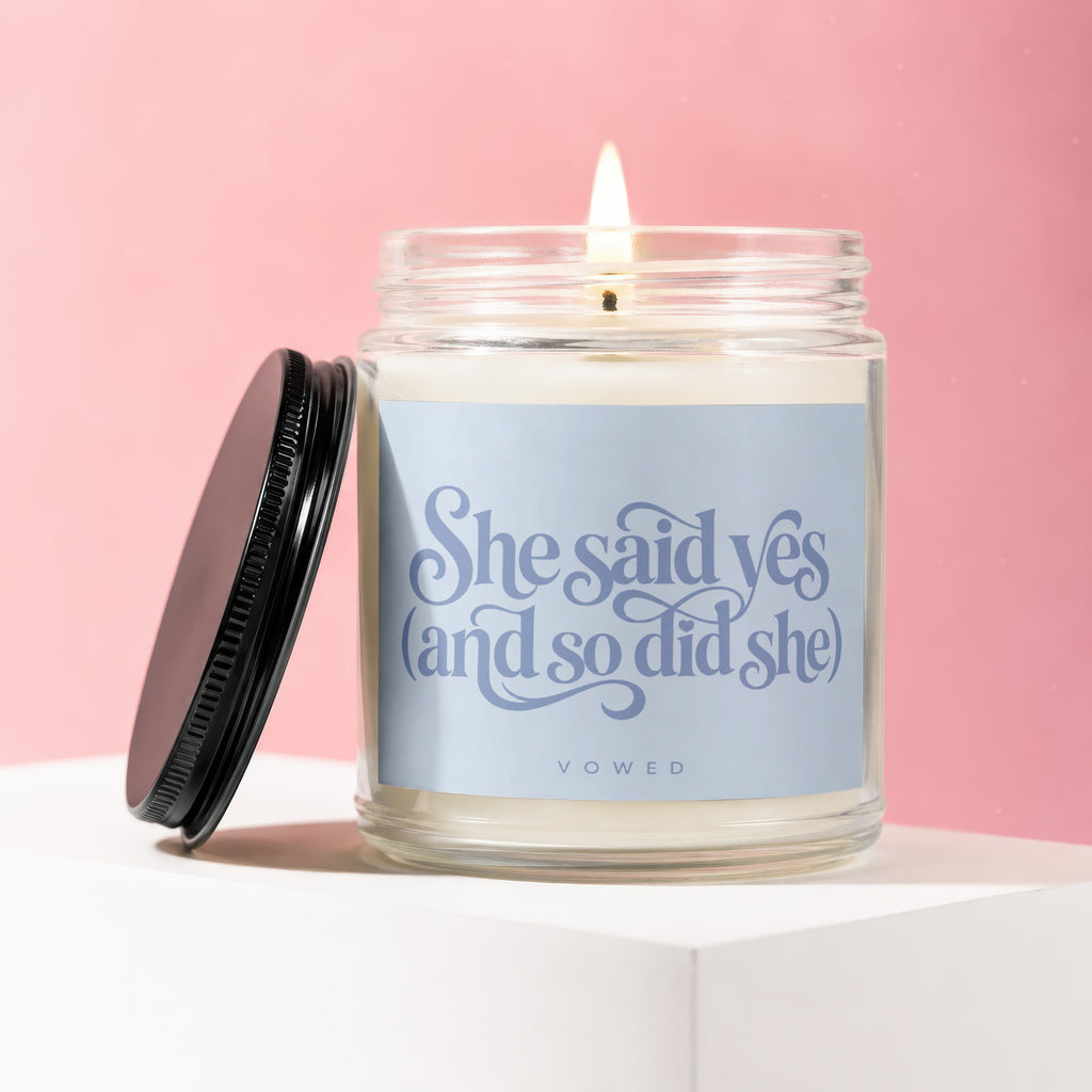 Lit candle with light blue label saying "She said yes (and so did she) VOWED"