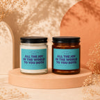 Two soy wax candles with blue labels reading "ALL THE JOY IN THE WORLD TO YOU BOTH".