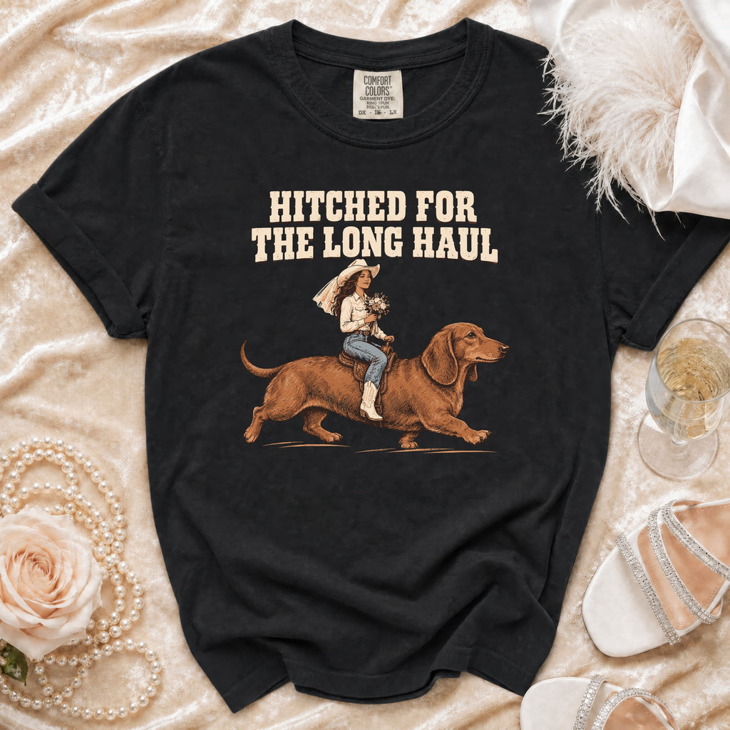 Black t-shirt with text "Hitched for the Long Haul" and illustration of bride riding a dachshund.