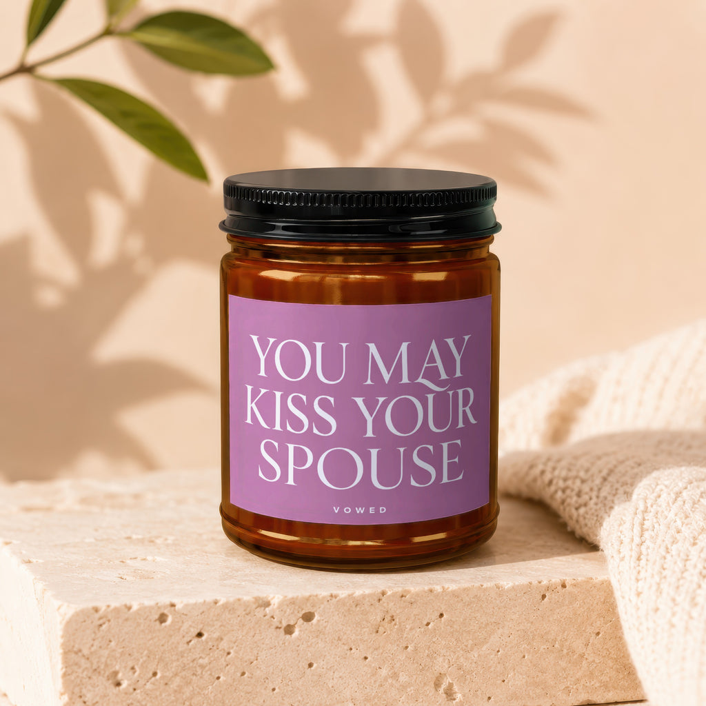 Amber jar candle with pink label reading, "YOU MAY KISS YOUR SPOUSE," and VOWED.
