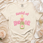 Cream t-shirt with "maid of HONOR" text and champagne bottle graphic.