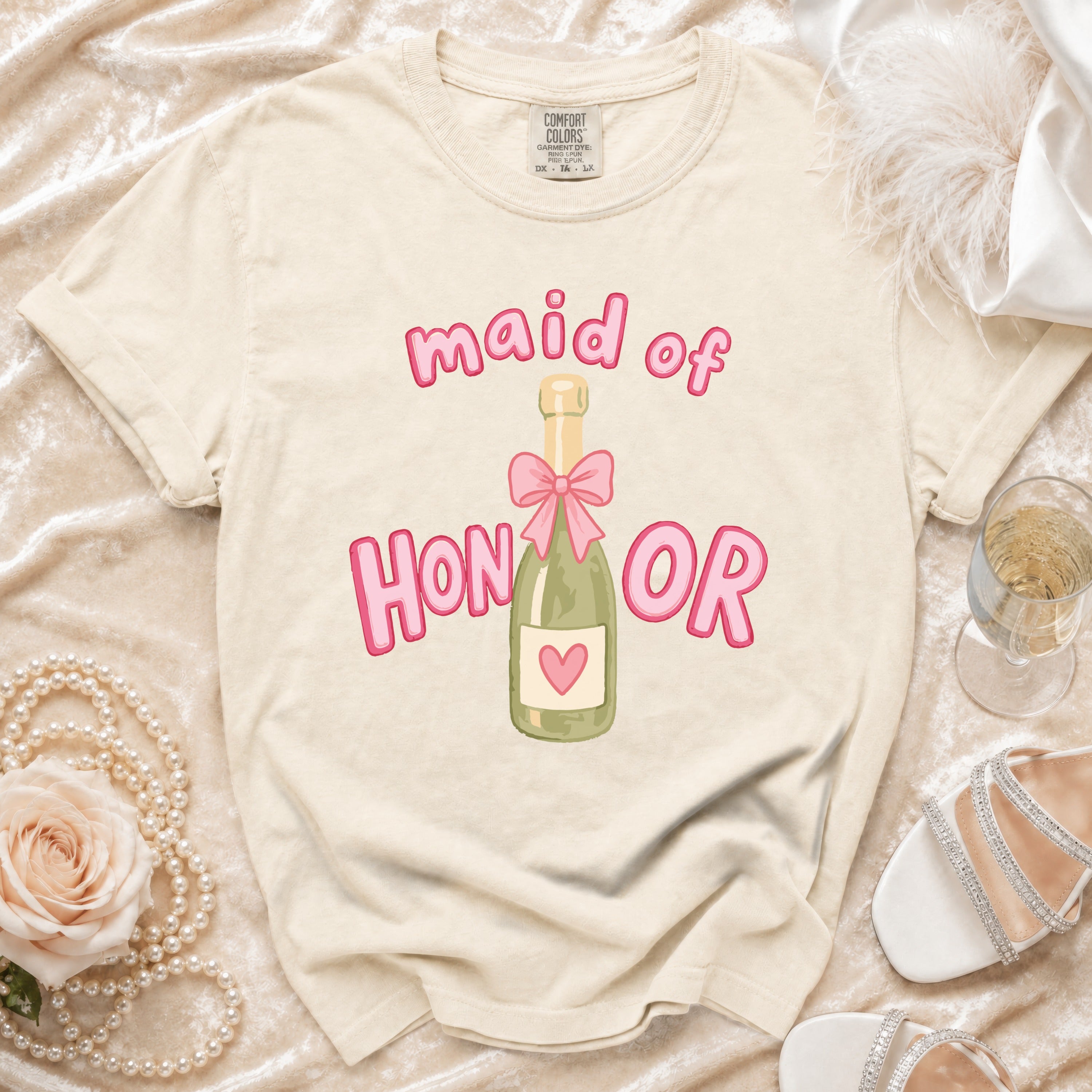 Cream t-shirt with "maid of HONOR" text and champagne bottle graphic.