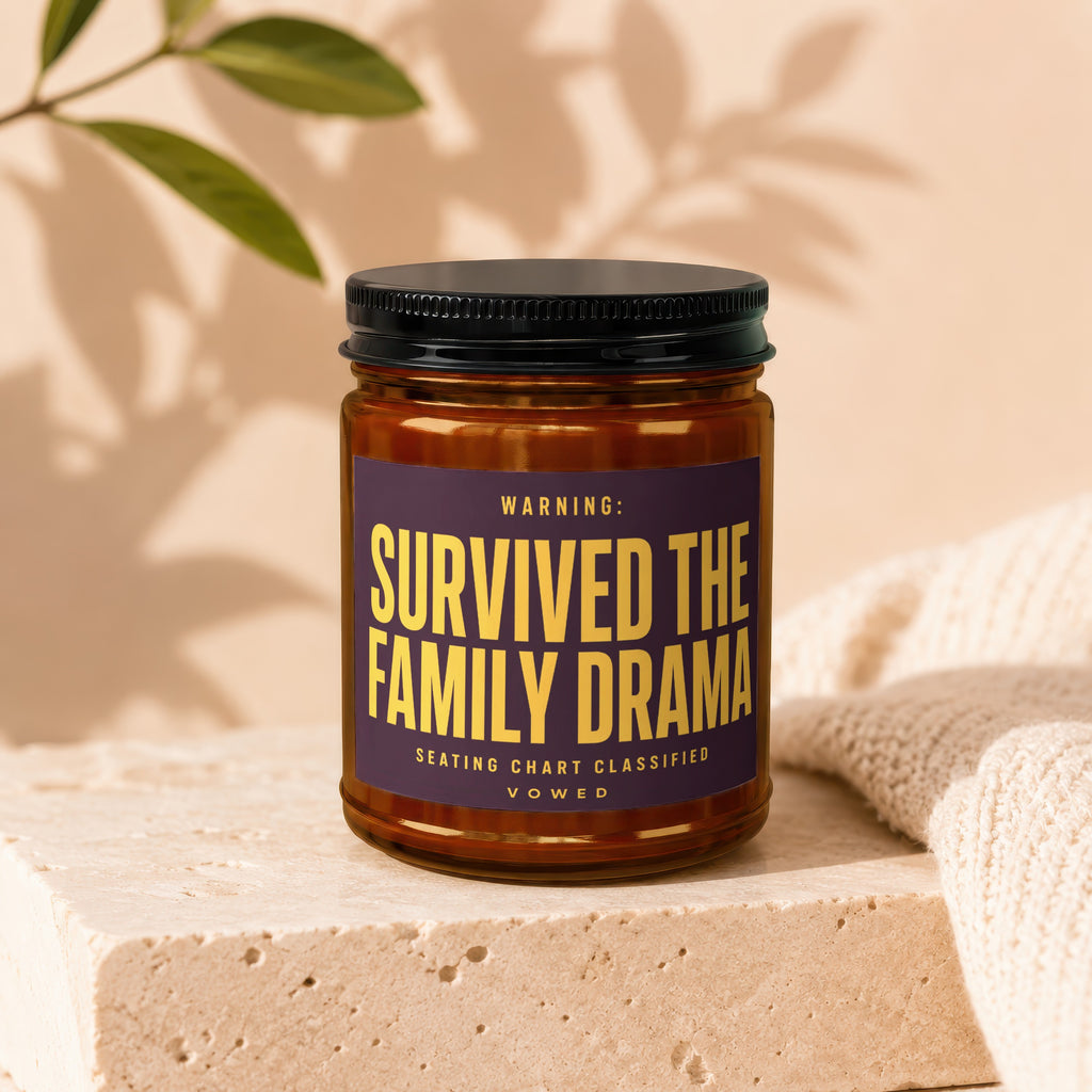 Amber jar candle with label "WARNING: SURVIVED THE FAMILY DRAMA SEATING CHART CLASSIFIED VOWED".