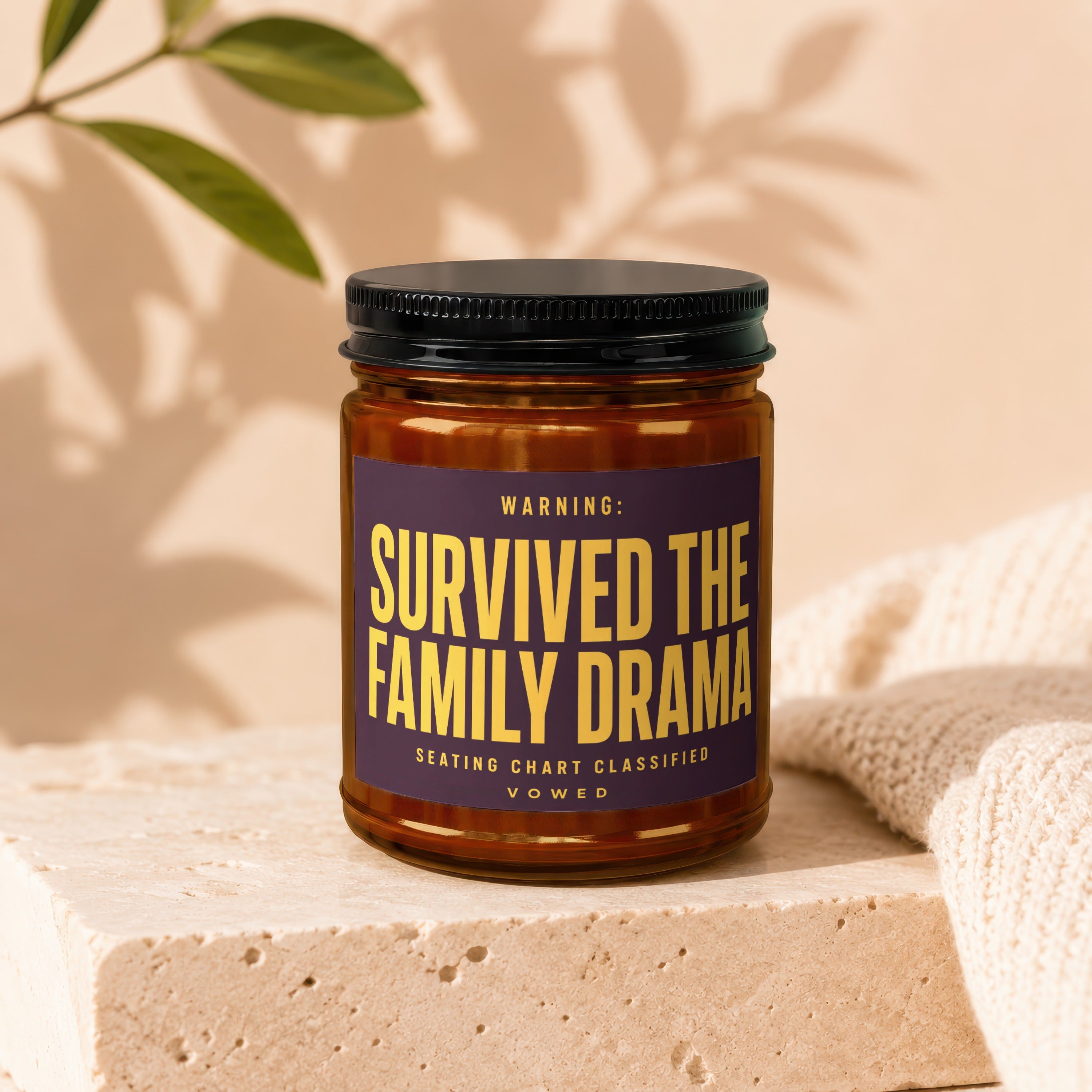 Amber jar candle with label "WARNING: SURVIVED THE FAMILY DRAMA SEATING CHART CLASSIFIED VOWED".