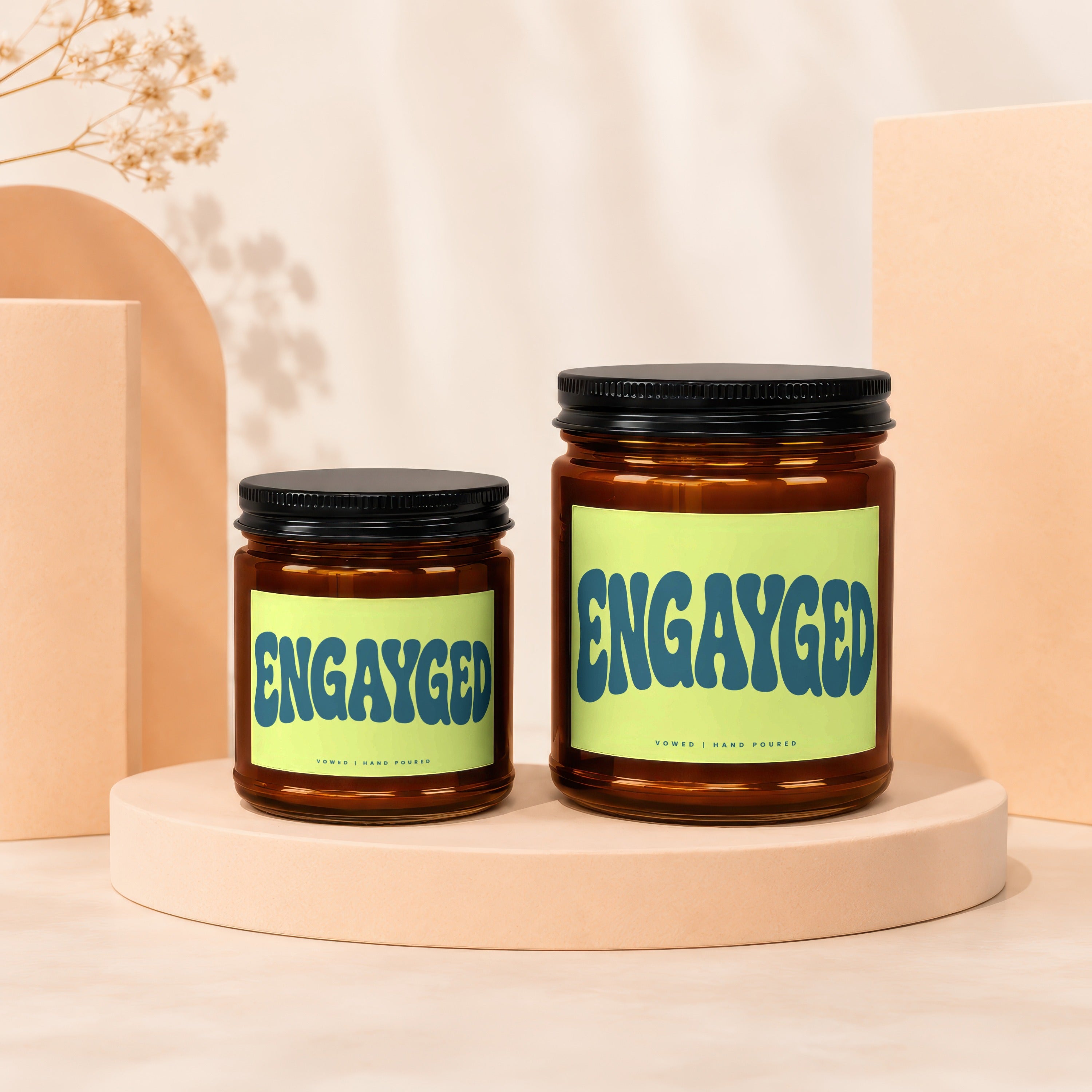 Two amber glass candles with "ENGAYGED" text on light green labels.