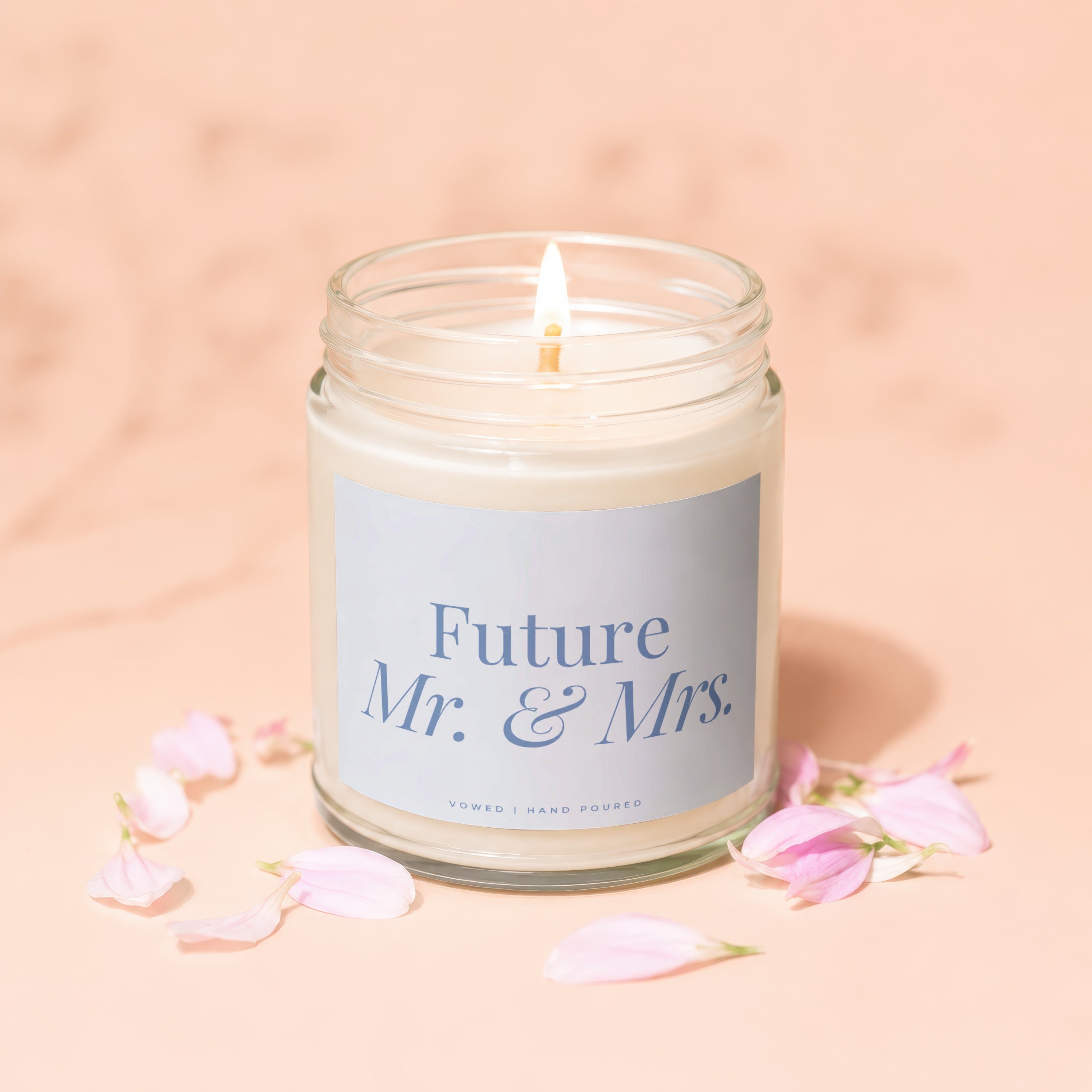 Lit candle with "Future Mr. & Mrs." text in glass jar, surrounded by pink petals.