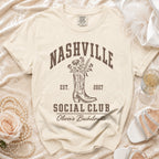 Cream t-shirt featuring brown text reading Nashville Social Club, a cowboy boot, flowers, and Olivia's Bachelorette.