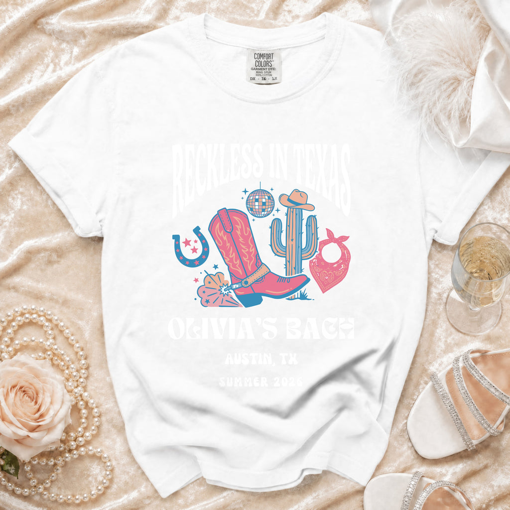 White t-shirt with "Reckless in Texas" and "Olivia's Bach" for Austin, TX Summer 2026.