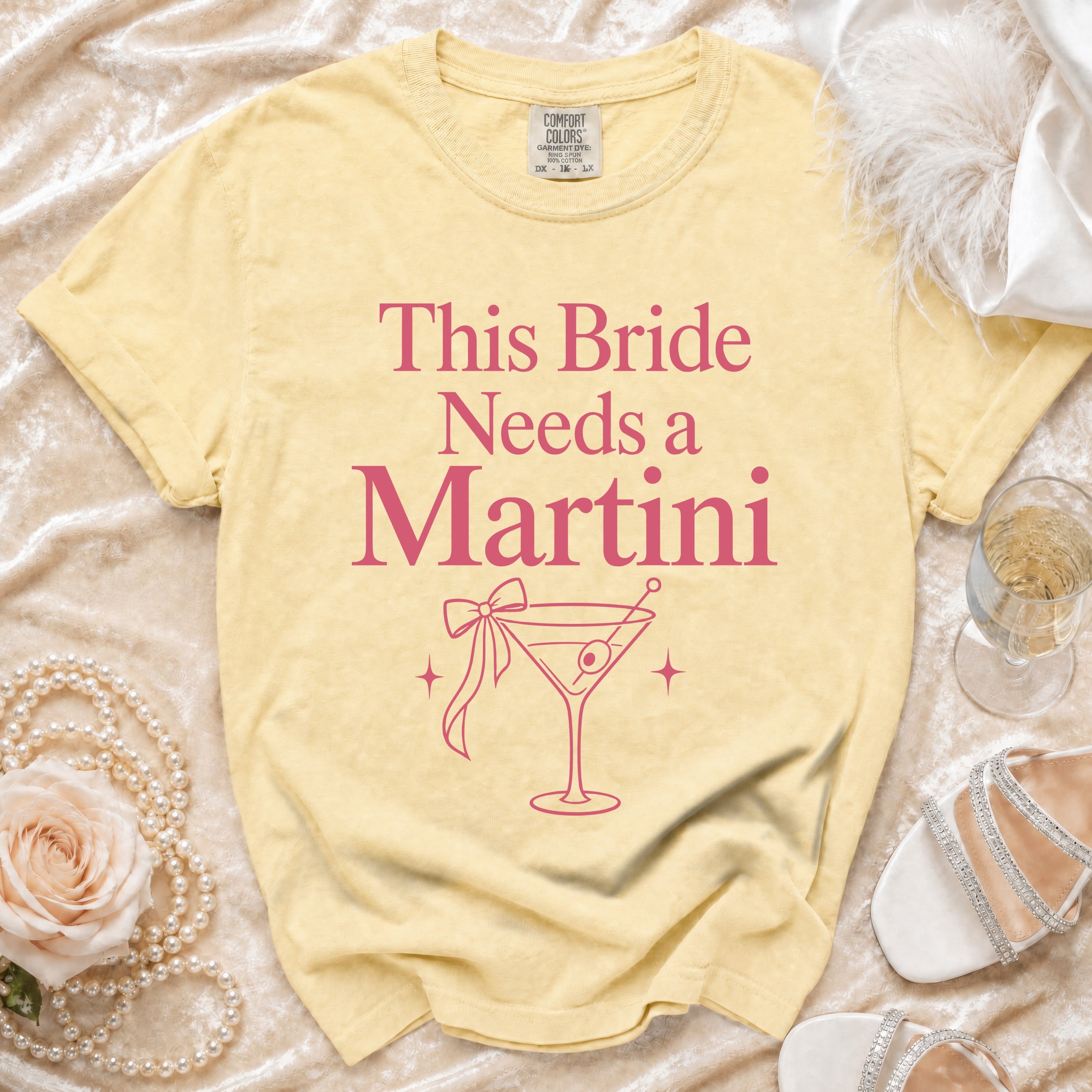 Yellow t-shirt with pink text "This Bride Needs a Martini" and martini glass graphic.