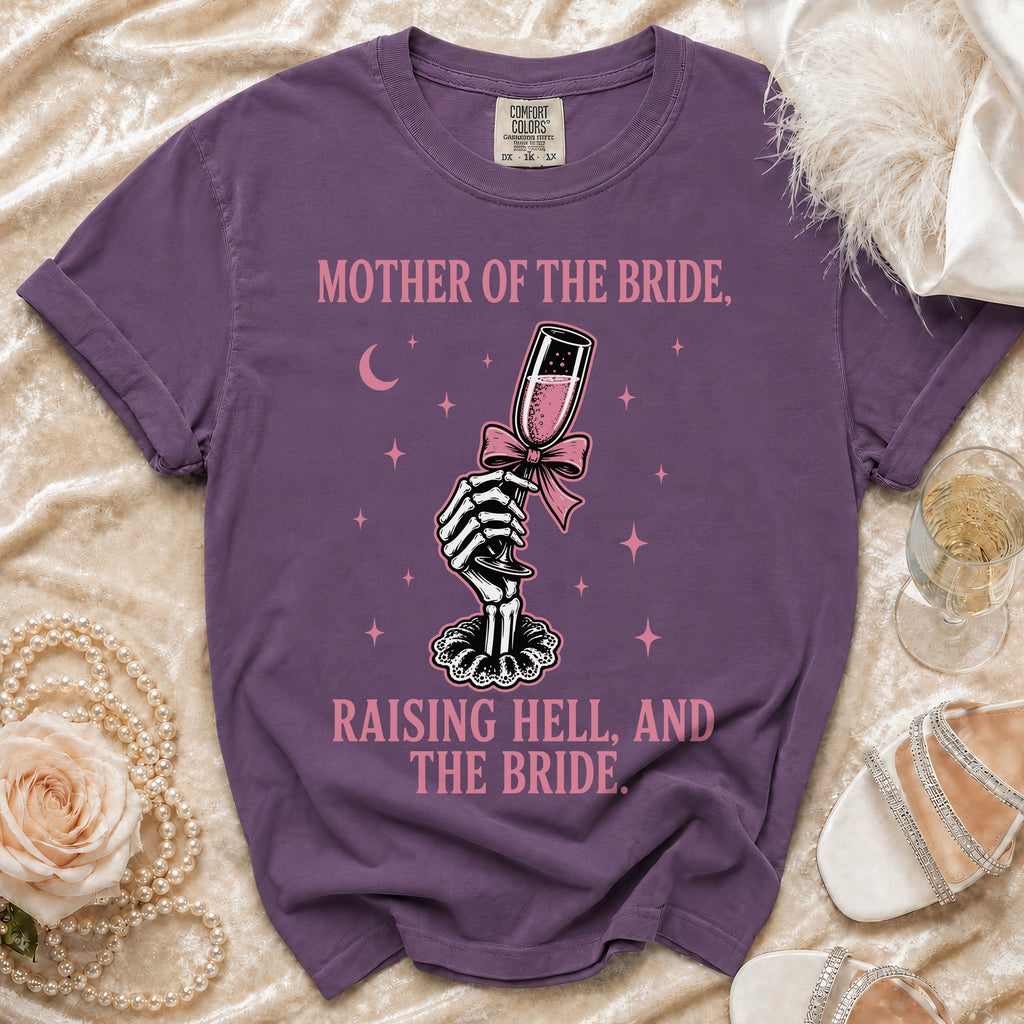 Purple t-shirt with skeleton hand holding champagne glass and text "Mother of the Bride, Raising Hell, and The Bride."