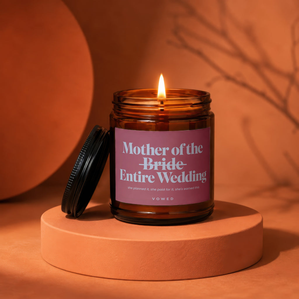 "Mother of the Bride Entire Wedding" candle with lit flame.