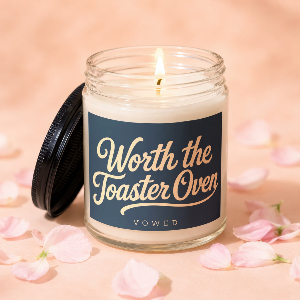 Lit candle in glass jar with dark lid, "Worth the Toaster Oven" text.