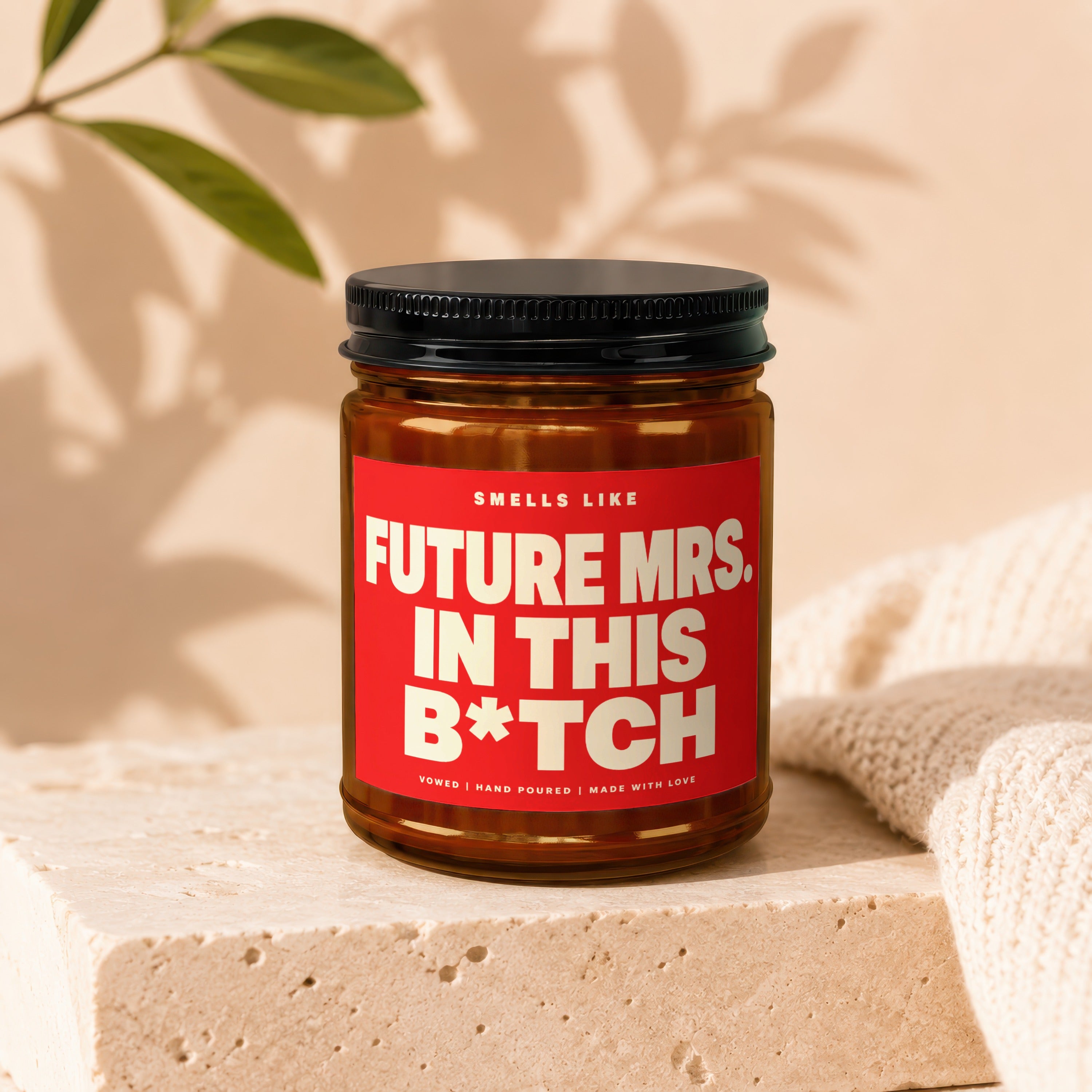 Candle with red label that reads "Smells Like Future Mrs. in This B*tch".