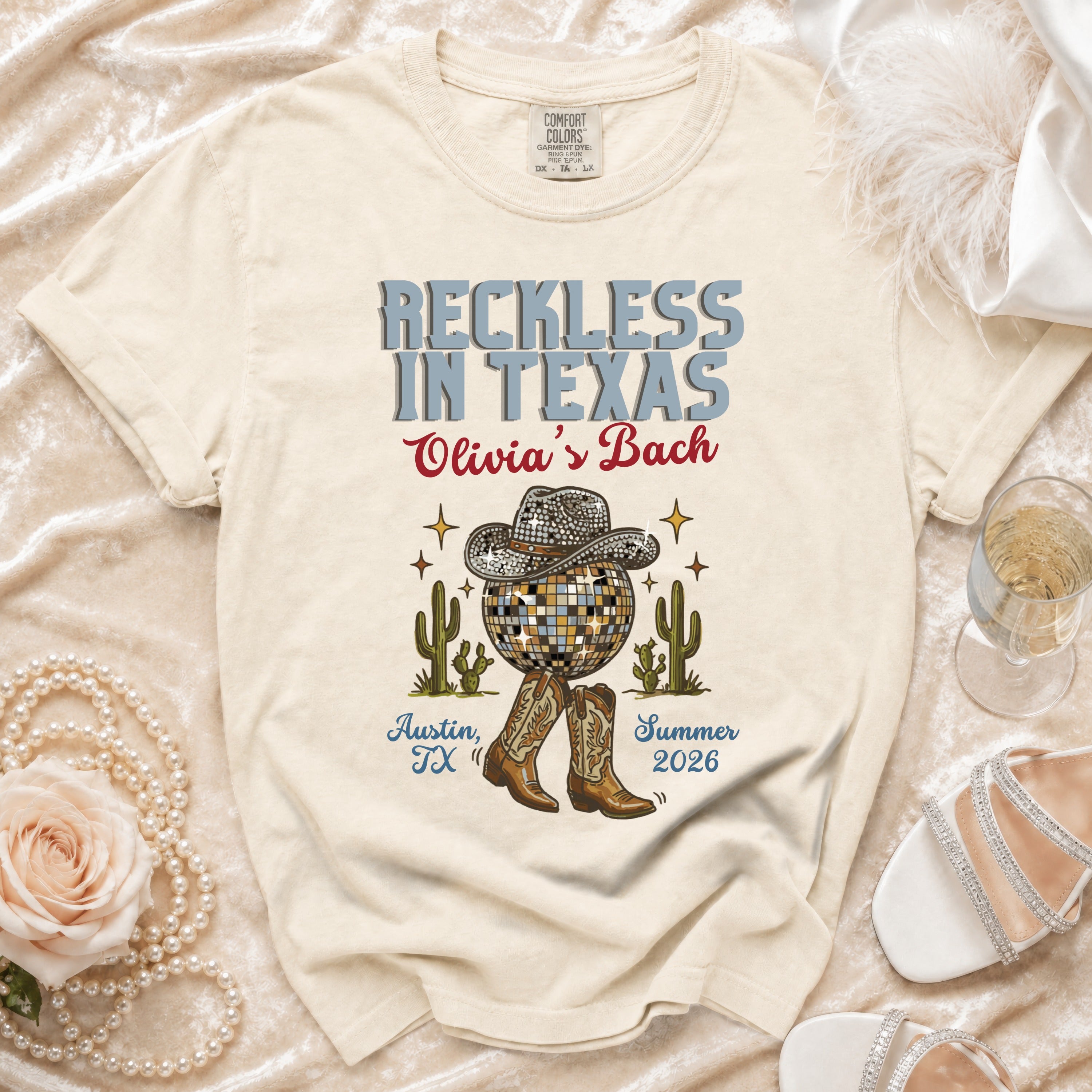 Cream t-shirt with "Reckless in Texas Olivia's Bach" text, disco ball, cacti, boots.
