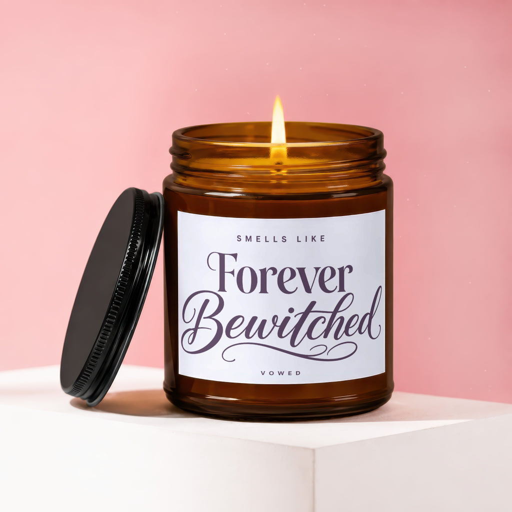 Amber jar candle with lit flame, lid open, reads "Smells Like Forever Bewitched".