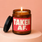 Amber jar candle with red label that says "TAKEN AF. VOWED."