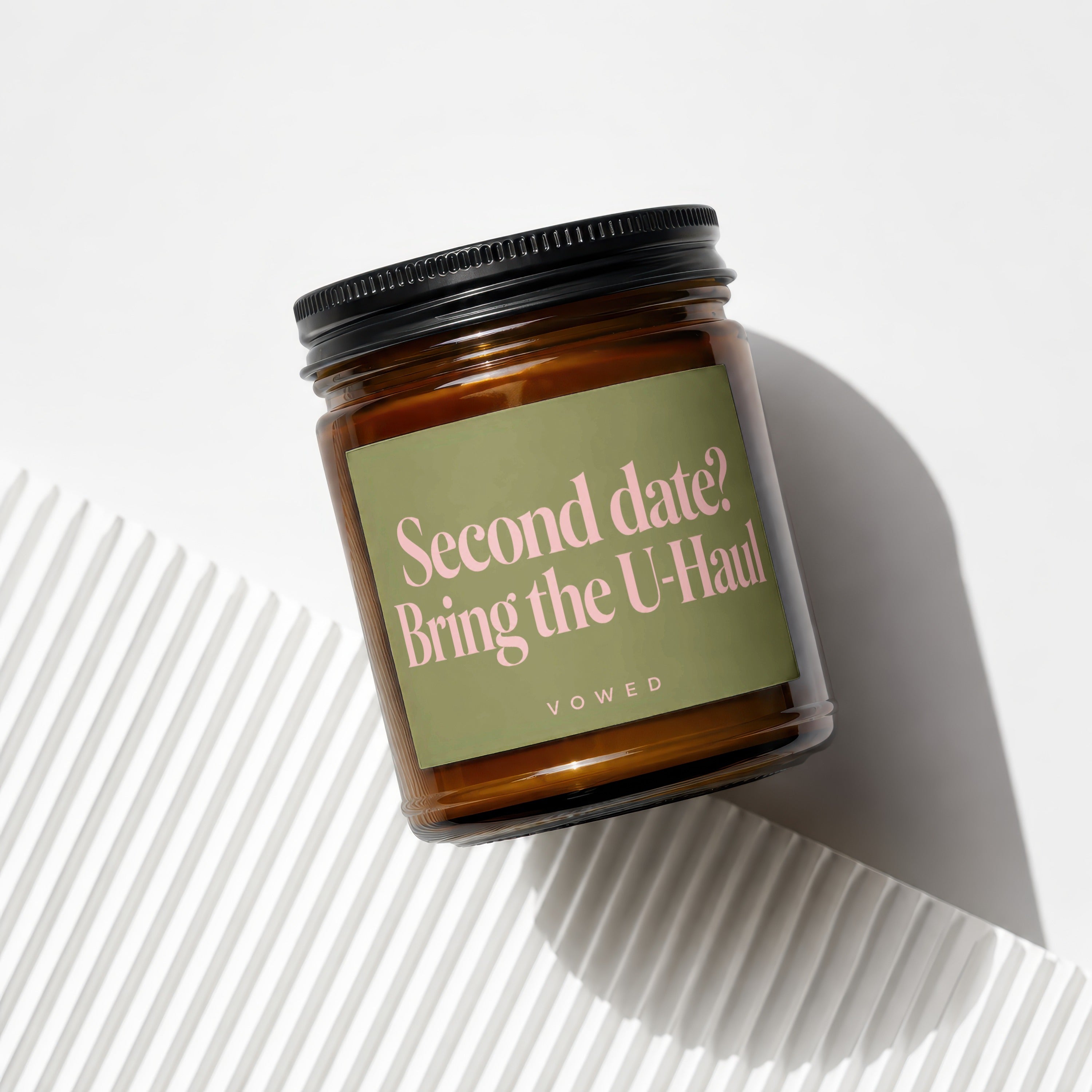 Amber glass candle with a green label reading "Second date? Bring the U-Haul".