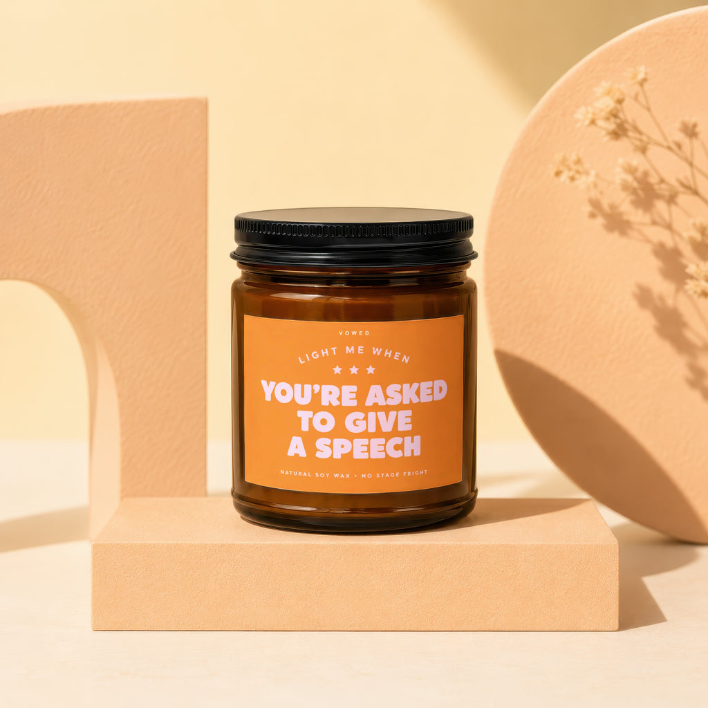 Amber glass candle with orange label reading "Light me when you're asked to give a speech."