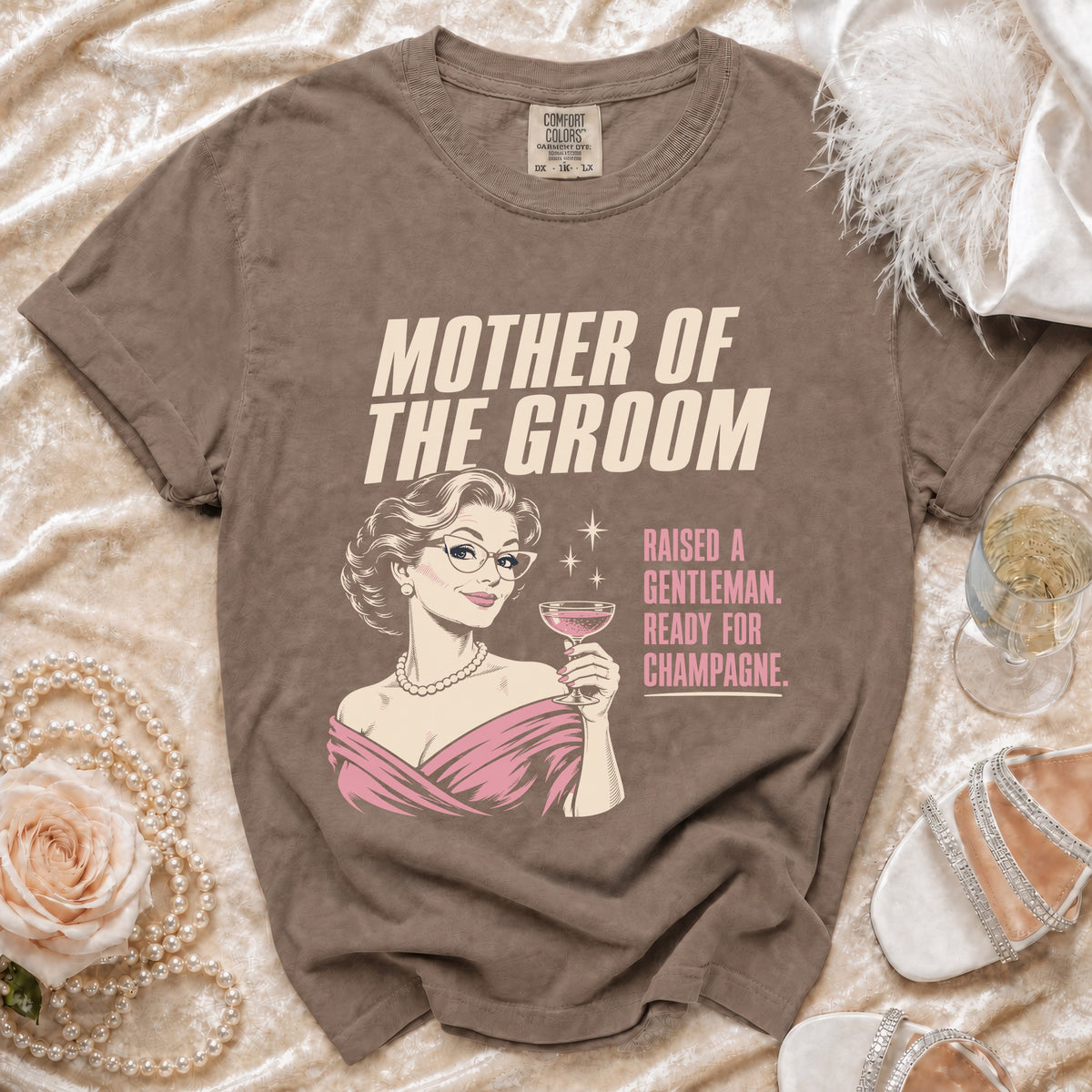 T-shirt with "Mother of the Groom Raised a Gentleman Ready for Champagne" text.