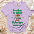 Purple t-shirt with "Reckless in Texas" and "Olivia's Bach Austin, TX Summer 2026".
