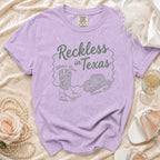 Purple t-shirt with "Reckless in Texas" text, cowboy boot, hat, and Austin TX details.