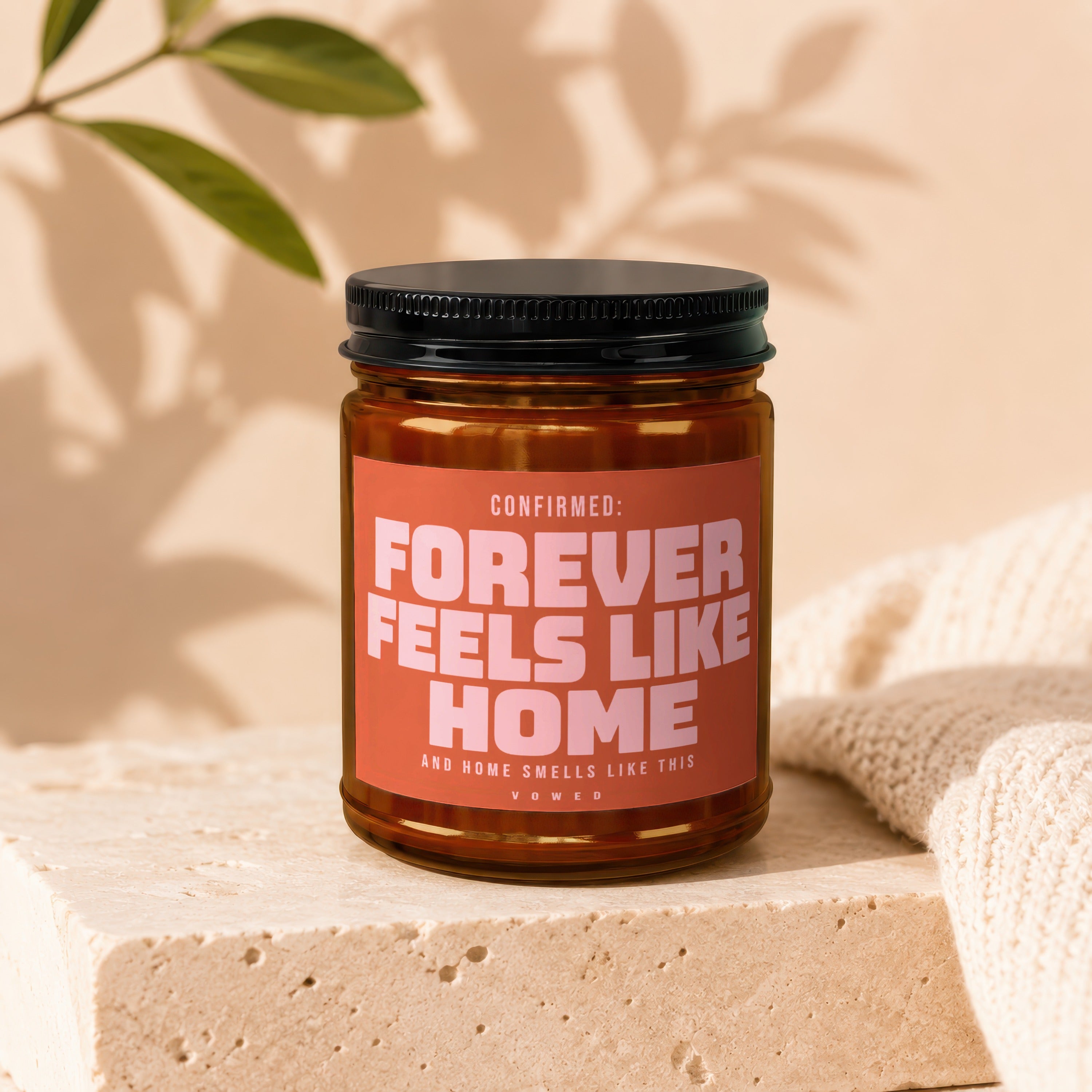 Candle with text "CONFIRMED: FOREVER FEELS LIKE HOME AND HOME SMELLS LIKE THIS VOWED".
