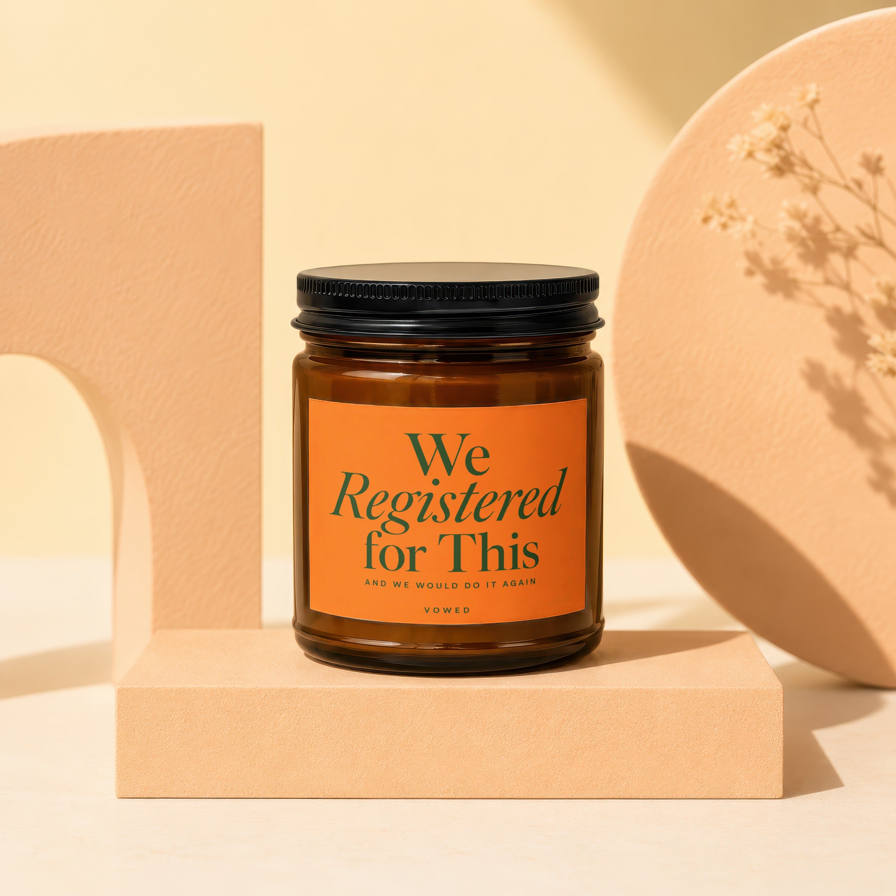 Amber jar candle with orange label reading "We Registered for This"