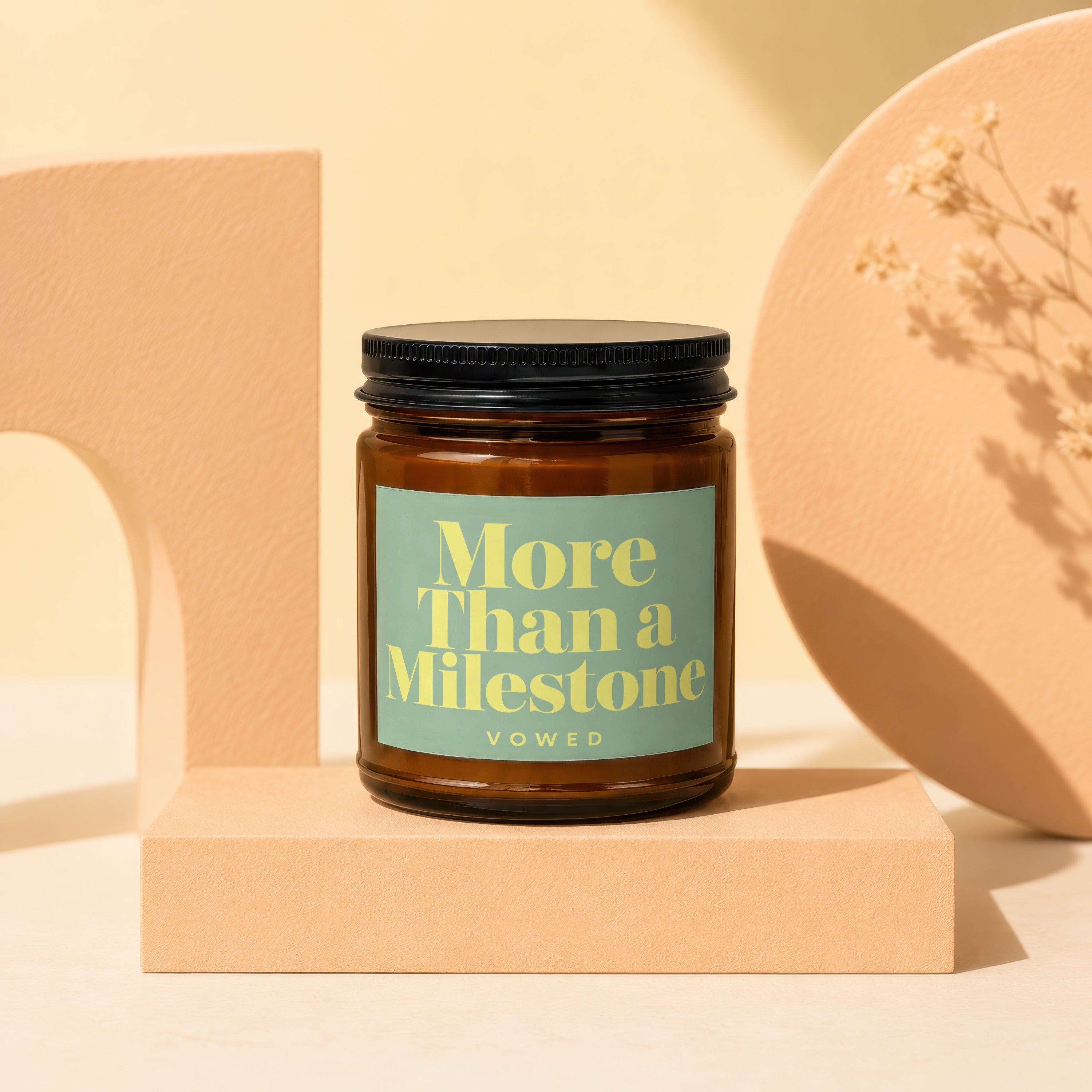 Amber jar candle with "More Than a Milestone" text on a light green label.