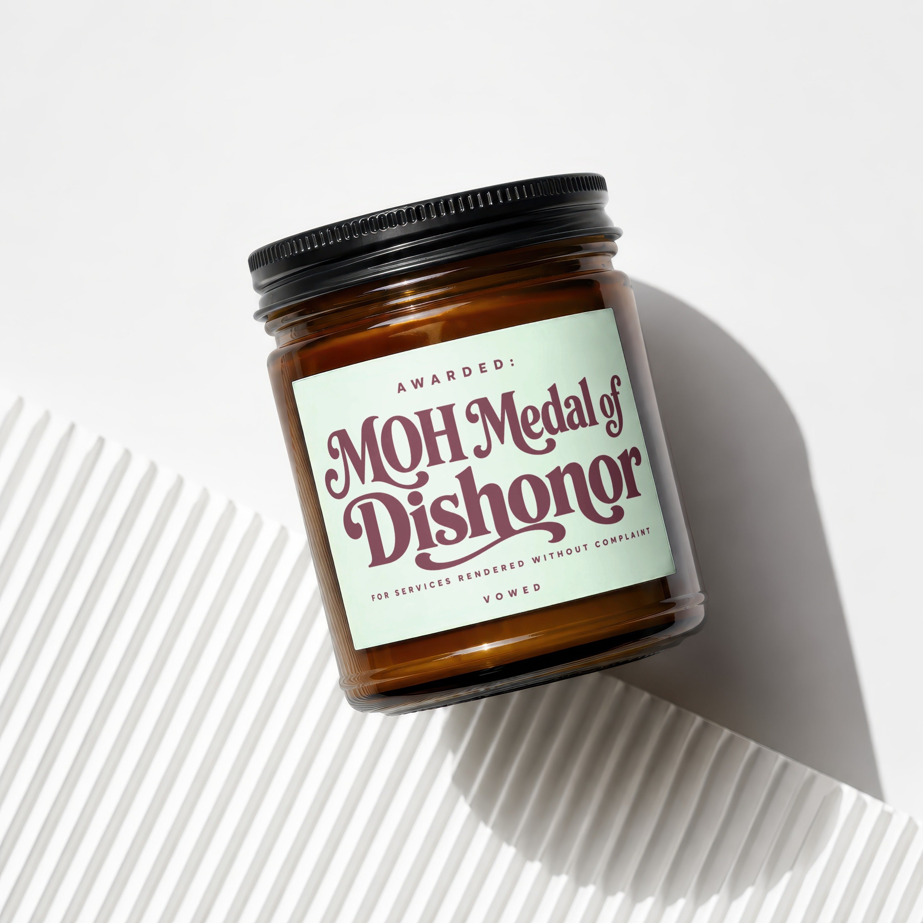 Amber jar candle with light green label reading "MOH Medal of Dishonor".