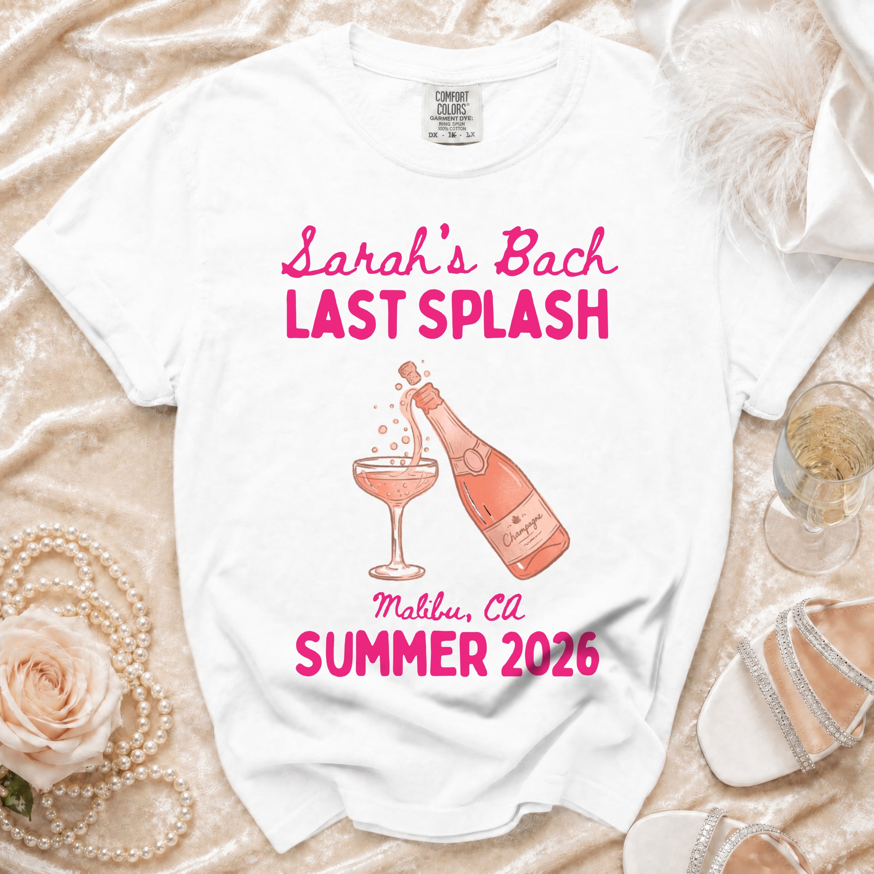 White t-shirt with pink text "Sarah's Bach LAST SPLASH" and champagne bottle.