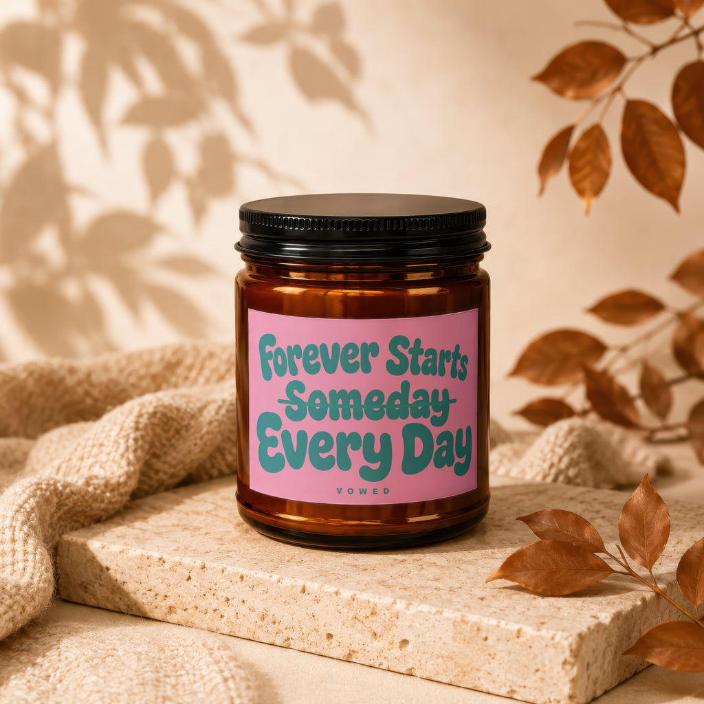 Candle with pink label reading "Forever Starts Someday Every Day" on stone.