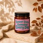 Candle with pink label reading "Forever Starts Someday Every Day" on stone.