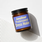Amber jar with black lid, blue label reads "Amateur Professional Dress Holder".