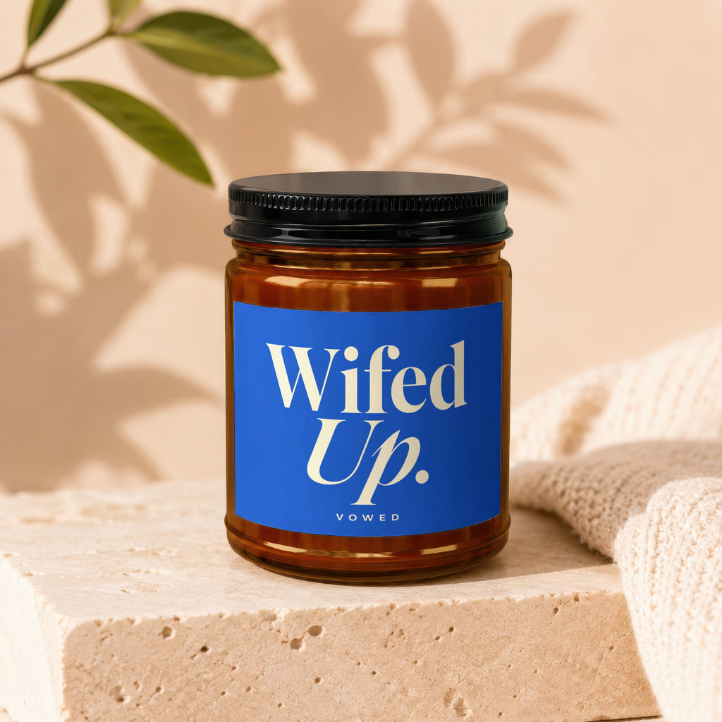 Amber candle in a glass jar with a blue label that reads "Wifed Up. vowed".